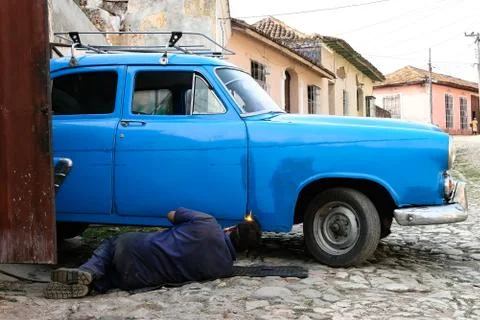 Trinidad, Cuba - April 7 2009 : Man repairing an old American car in the stre Stock Photos