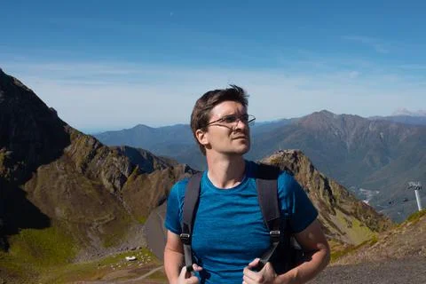 Trip in the mountains. A young man with a backpack is walking in the mountains. Stock Photos