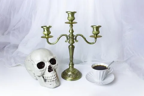 Triple candelabrum with three candlesticks, human skull and porcelain coffee Stock Photos
