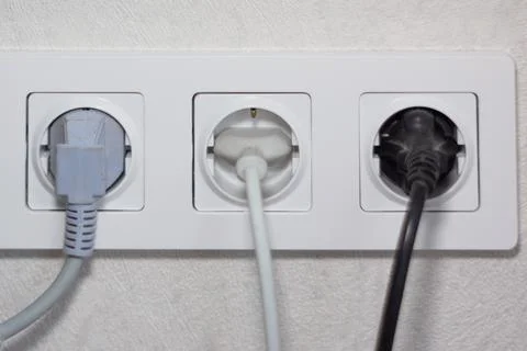 Triple electrical socket with electrical plugs plugged into it Stock Photos