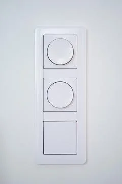 Triple light switch with dimmer on white wall Stock Photos