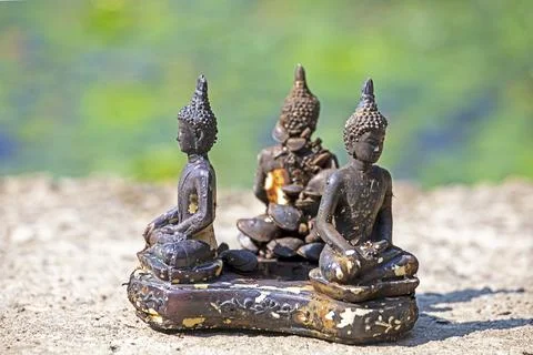 A triple statue of a buda (candlestick) with live shellfish near a pond Stock Photos