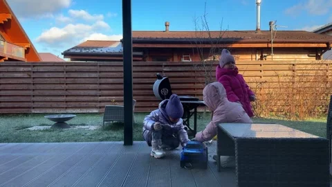 Triplet sisters playing in winter in the backyard, clear cold weather children Video stock 266299923