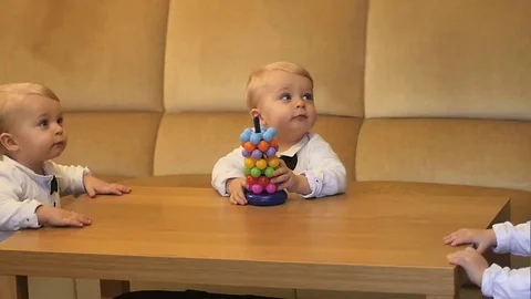 Triplets on session - 3 same infants in festive clothes standing near table Stock Footage 83726715