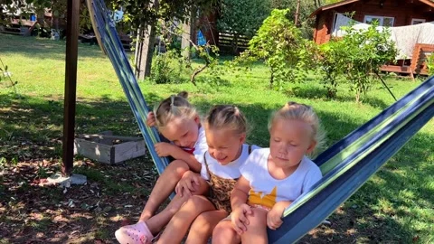 Triplets Sisters swinging on a hammock 库存影片 252490818