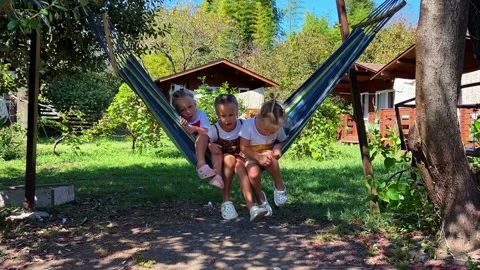 Triplets Sisters swinging on a hammock 库存影片 252490835