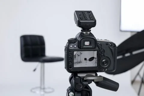 Tripod with camera, bar stool and professional lighting equipment in modern.. Foto stock