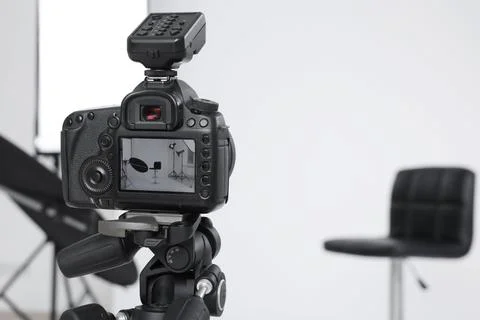 Tripod with camera, bar stool and professional lighting equipment in modern.. Foto stock
