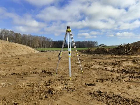 Tripod setup on construction site with cloudy sky and dirt landscape Stock Photos