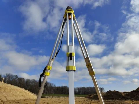 Tripod setup for land surveying on construction site under blue sky Stock Photos
