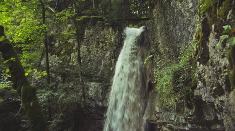 A Tripod shot of a waterfall flowing through rough rocks in a green forrest Video stock 63225070