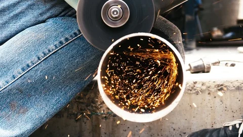 Tripod: Worker in jeans cutting through a steel pipe with angle grinder Stock Footage 91499376