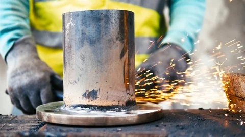 Tripod: Worker wearing gloves working on steel pipe with angle grinder Stock Footage 91499981