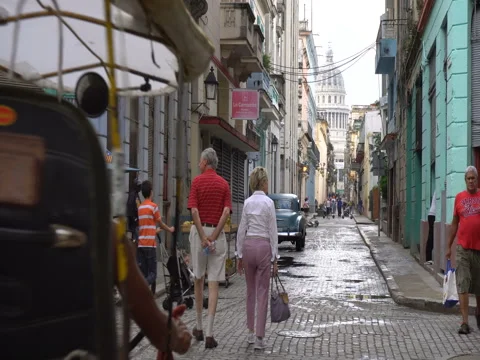 Trishaws with driver is parked on roadside. Other local taxi rides along narrow Stock Footage 70856500