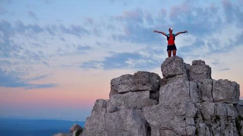 Triumphant Runner on Cliffs at Sunset Foto stock
