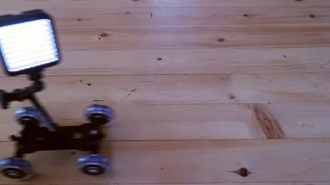 A trolley on wheels with a lighting device rolls on the wooden floor 스톡 동영상 144884629