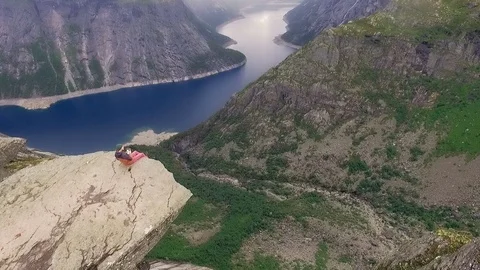 Trolltunga. The guy sitting on the edge of the stone Stock-Footage 69785128