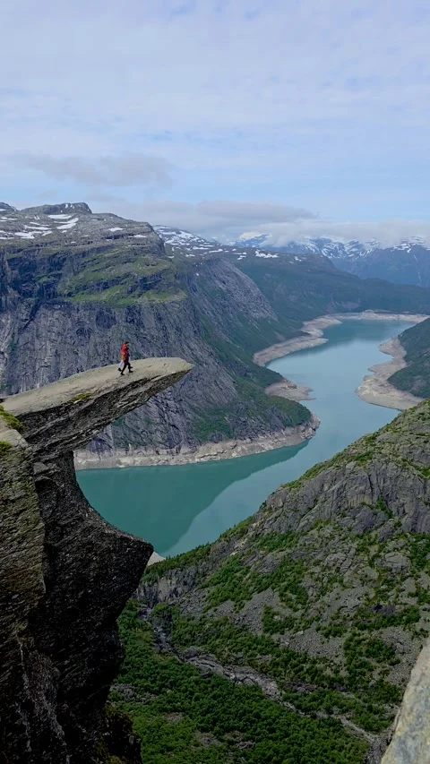 Trolltunga, Norway, two people standing on a cliff overlooking a lake, Vídeos de archivo 280347879