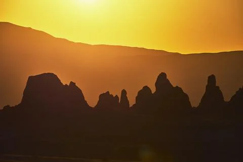 Trona Pinnacles Silhouette at Golden Hour with Mountains and Dramatic Sunligh Stock Photos