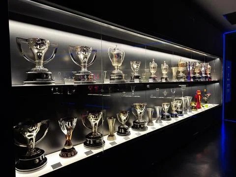 Trophy display case filled with silver cups and awards in a museum showcase.. Stock Photos