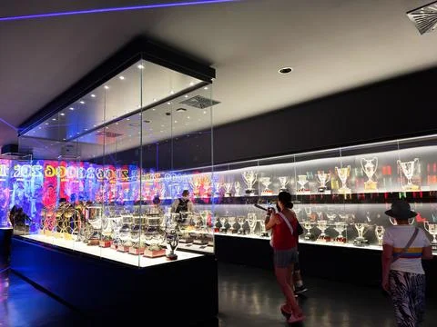 Trophy gallery with illuminated cup display and visitors in a modern sports.. Stock Photos