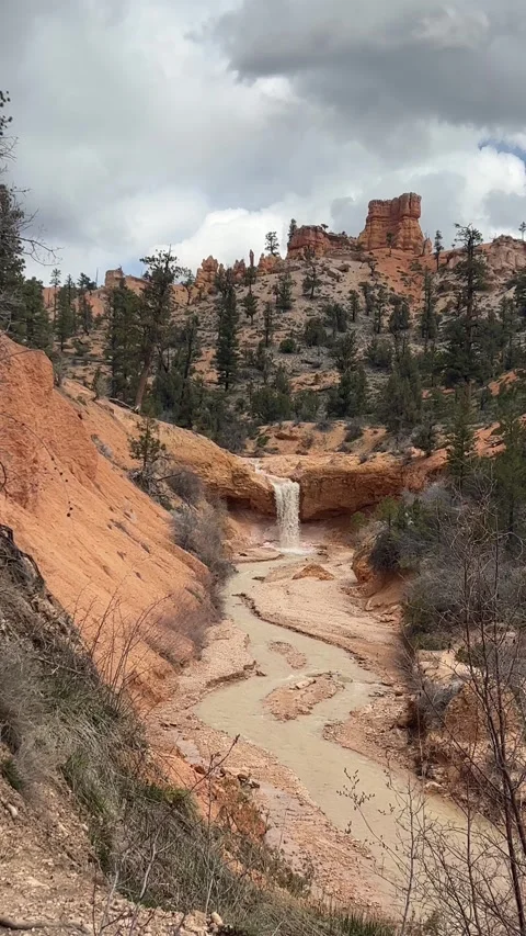Tropic Ditch Falls flows down red rock into a muddy Bryce Canyon stream Stock Footage 321506008
