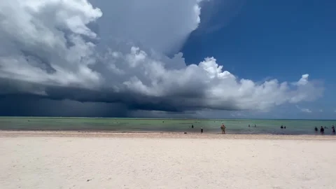 Tropical beach with approaching storm clouds and people enjoying the water Stock Footage 345259923