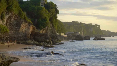 Tropical beach with big waves in slow motion and cliff during sunset with runnin Stock Footage 113269769
