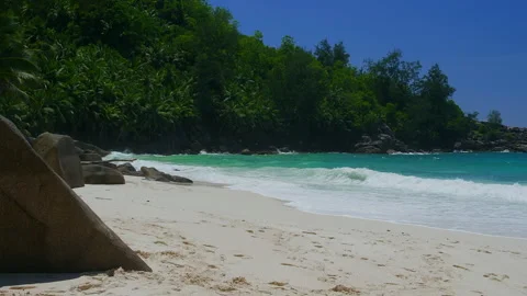 Tropical beach cove with turquoise waves, white sand, boulders, lush vegetation Stock Footage 346367048