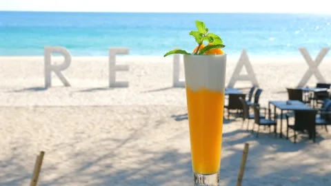 Tropical beach getaway concept with refreshing cocktail in foreground Stock Footage 264466080