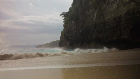 Tropical beach with powerful ocean waves crashing against a high cliff Stock Footage 341515645