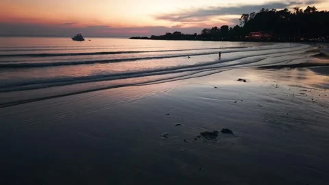 Tropical beach reflecting dramatic sunset at twilight with yacht and tourists Video stock 311751915