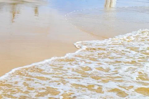 Tropical beach sand texture with clear waves and reflective ocean surface T.. Stock Photos