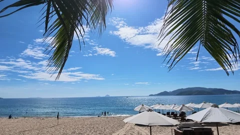 Tropical beach view with white umbrellas beach chairs and mountains Stock Footage 344024754