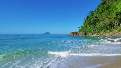 Tropical Beach Waves with Forested Cliff and Distant Island Video stock 343406493
