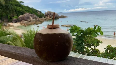 Tropical coconut drink with a straw against the backdrop of a golden beach, sea Stockbeeldmateriaal 243270853