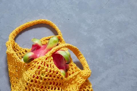 Tropical Dragon fruit in a string bag on a gray concrete background. Shopping Stock Photos
