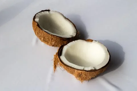 Tropical fruit concept, Two halves of fresh white coconut on white fabric b.. Stock Photos