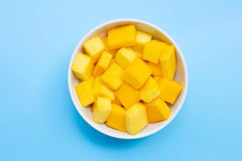 Tropical fruit, Mango cube slices in white bowl on blue background. Stock Photos