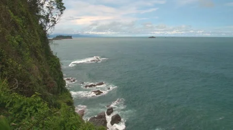Tropical green cliffs tower over surf Stock Footage 1032715