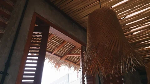 Tropical interior featuring a wicker lampshade and a wooden shutter window. Video stock 343406214