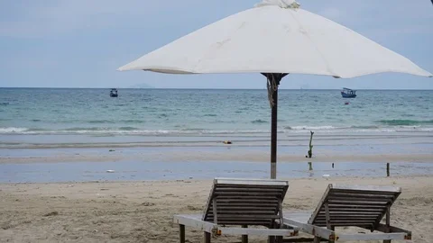 Tropical island sea shore and two deckchairs under parasol time lapse. Stock Footage