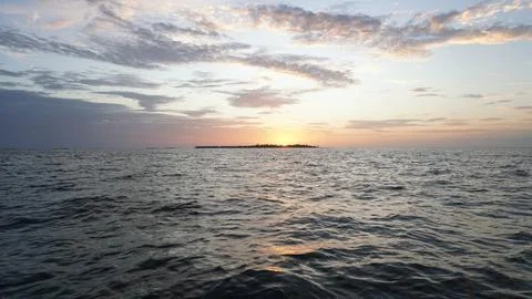 Tropical island sunset over calm ocean waters in the maldives Stock Photos