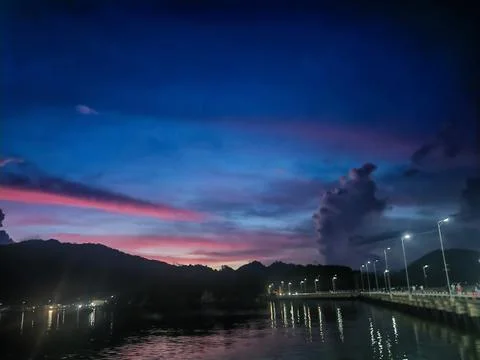 Tropical Nightfall with Pink Cloud Formations over Mountain Range 库存照片