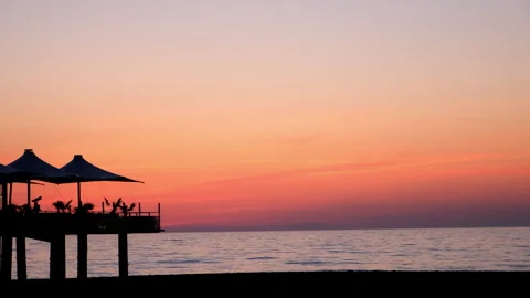 Tropical ocean beach with cafe on beach at dark sunset with purple orange sky. Stock Footage 246288017
