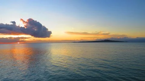 Tropical Ocean Sunset with Dramatic Clouds and Island Silhouette 스톡 사진