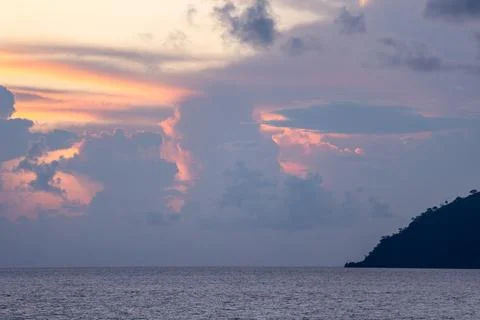 Tropical Ocean Sunset with Voluminous Clouds and a Dark Island Silhouette Stock Photos
