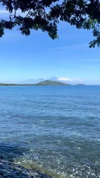 Tropical Ocean View with Distant Mountain Framed by Tree Branches Stock Photos