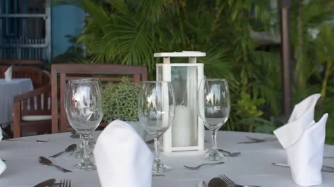 Tropical outdoor dinner table set up with elegant dinnerware and lantern Stock Footage 313279316