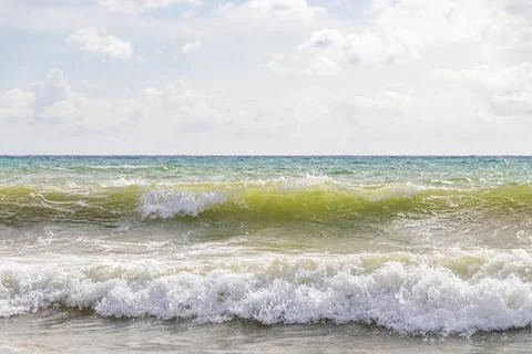 Tropical paradise waves rolling beneath vibrant cloudy blue coastal atmosph.. Stock-Fotos